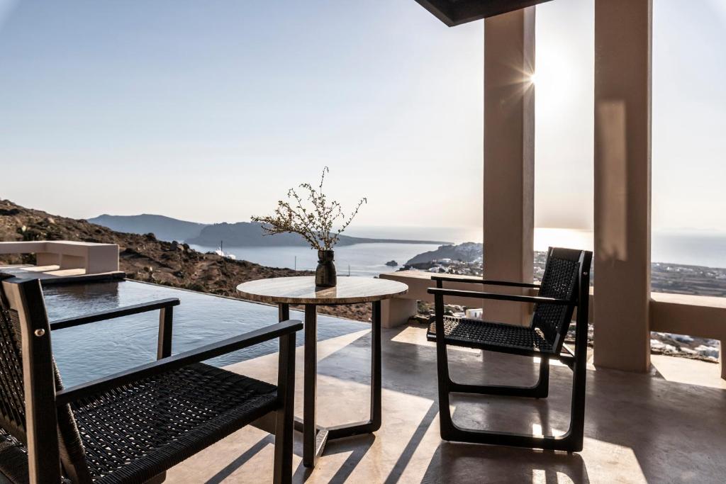 un tavolo e sedie su un balcone con vista sull'oceano di Nimbus Santorini a Oia