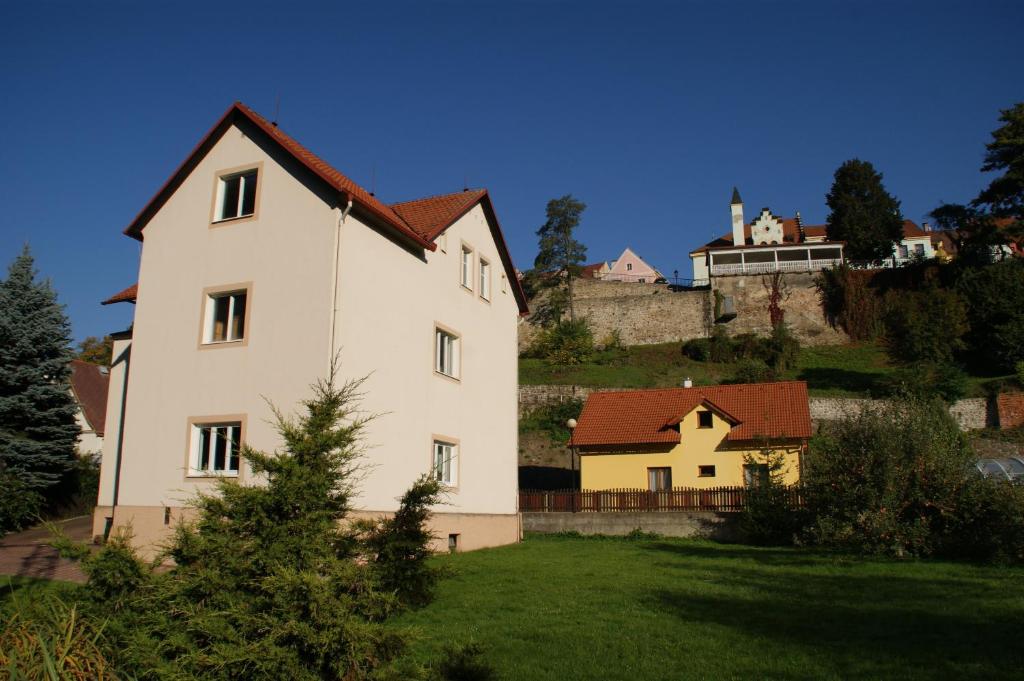 una gran casa blanca en una colina con un patio verde en Ubytování pod Jezem, en Loket