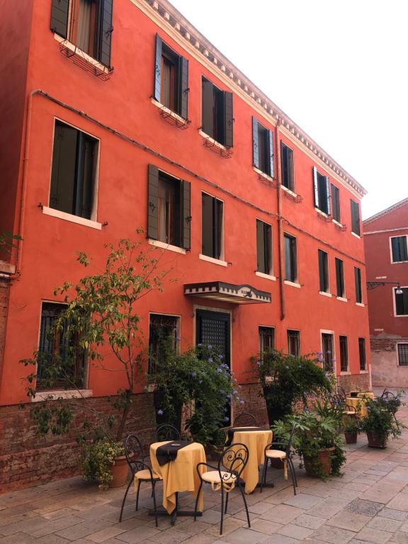 威尼斯的住宿－阿爾伯格瑪林酒店，前面有桌椅的红色建筑
