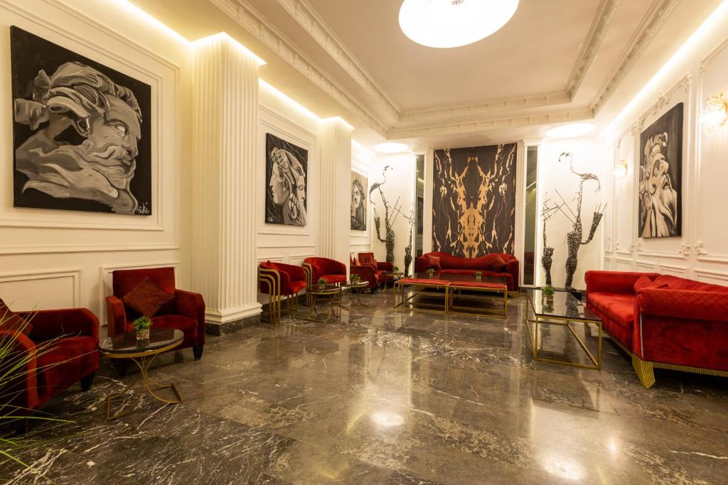 a waiting room with red chairs and paintings on the walls at Hotel Majestic in Casablanca