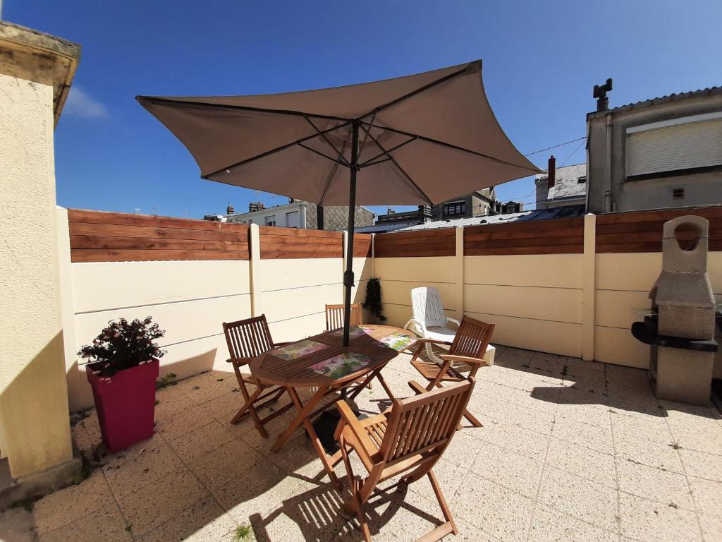 une table et des chaises avec un parasol sur une terrasse dans l'établissement Fleur d'écume, à Berck-sur-Mer