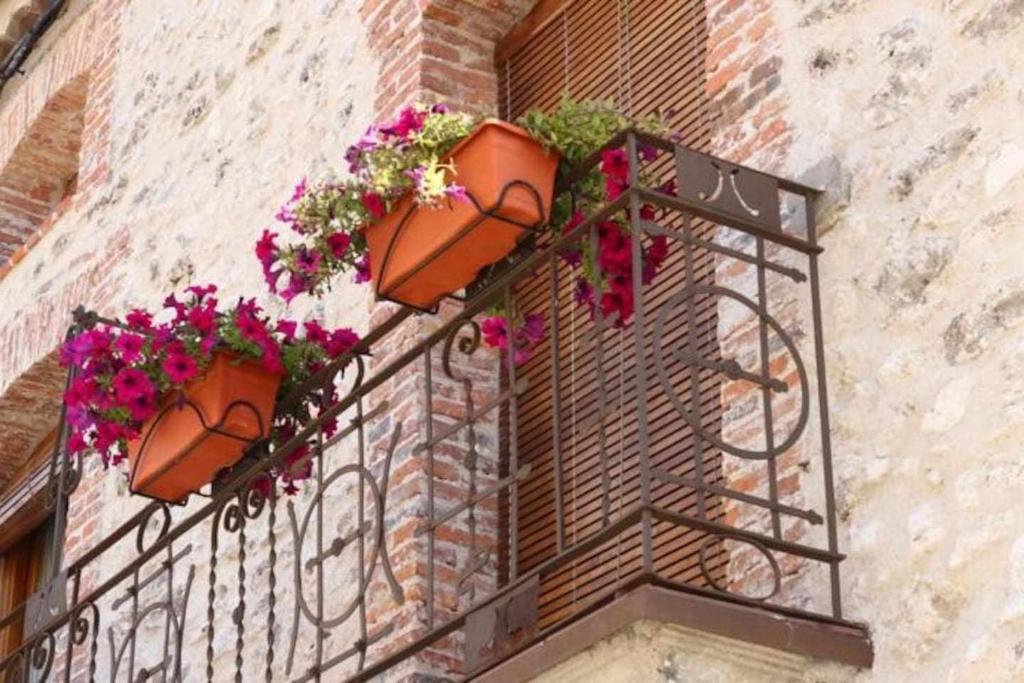 einen Balkon mit Blumentöpfen auf einem Backsteingebäude in der Unterkunft Casa Rural San Roque in Fuenterrebollo