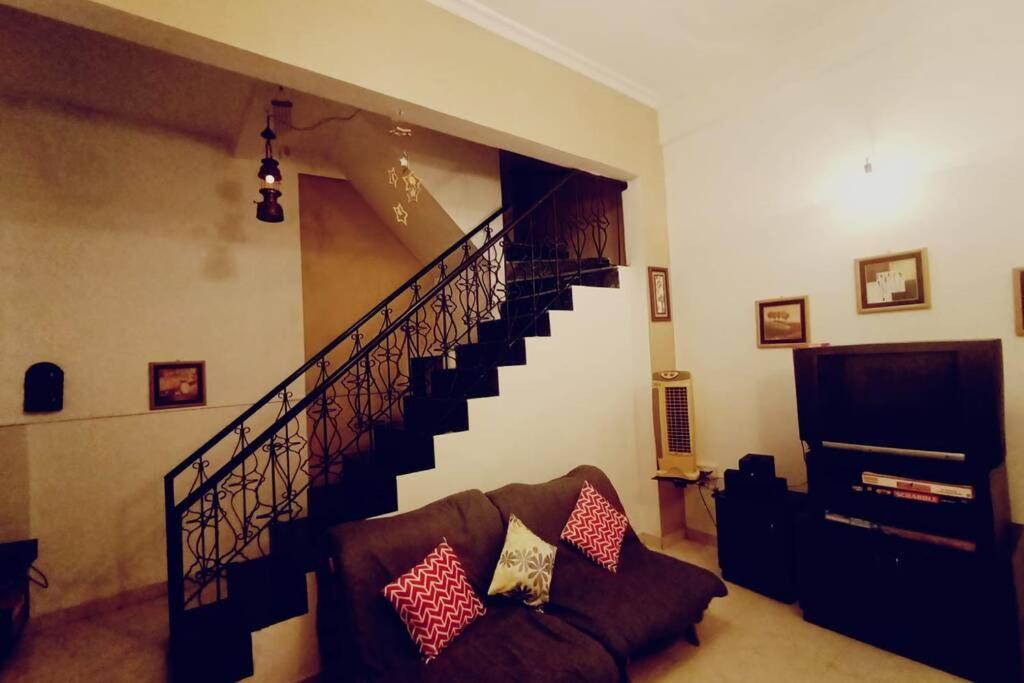 a living room with a staircase and a couch at Ivy Garden View, 2 BHK Private House, Lonavala in Lonavala