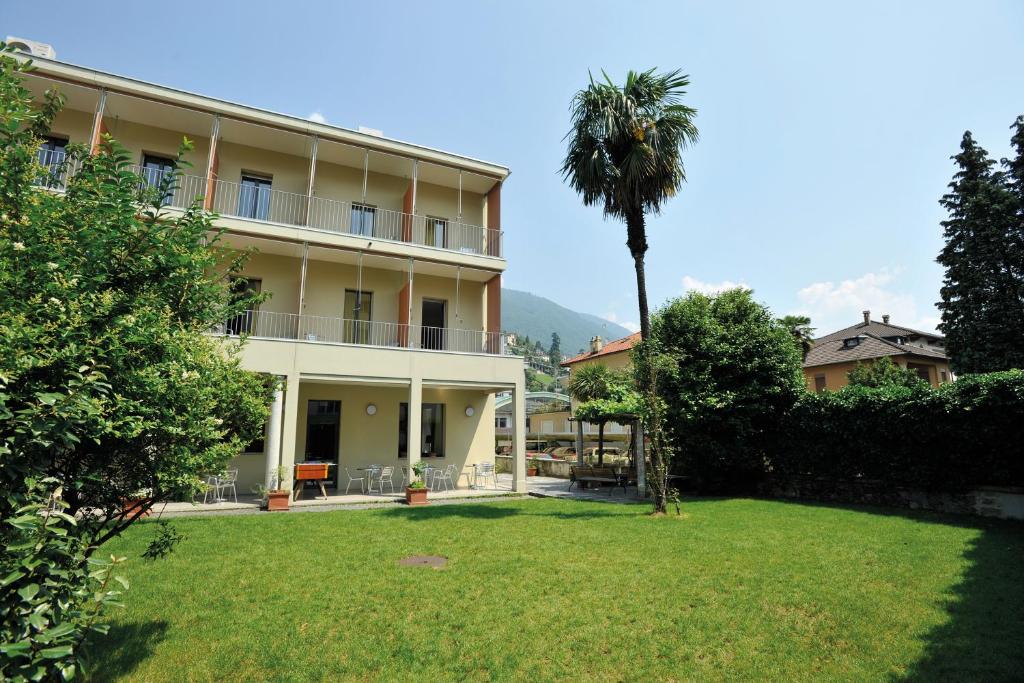 un edificio con una palmera y un patio en Locarno Youth Hostel, en Locarno