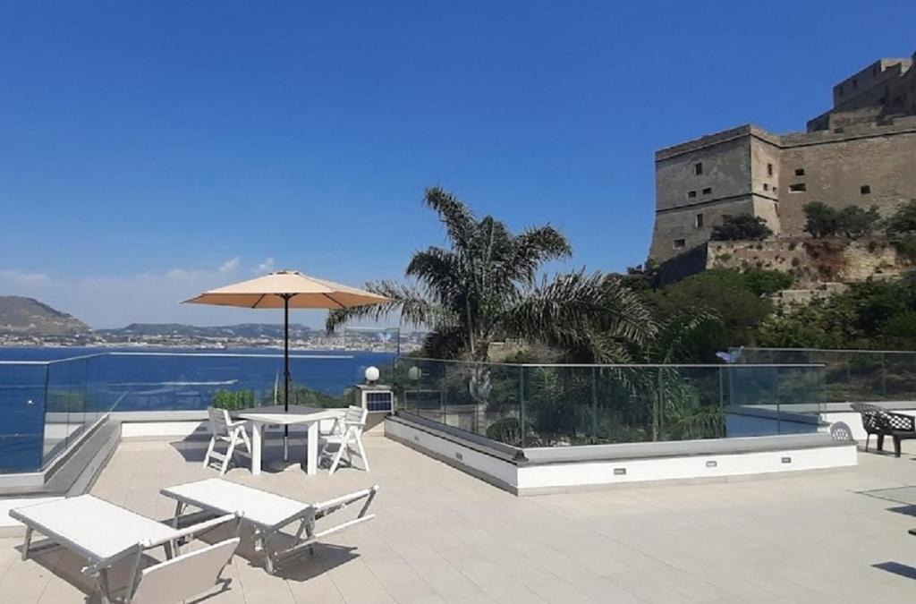 patio ze stołem, krzesłami i parasolem w obiekcie Villa Principe w mieście Bacoli