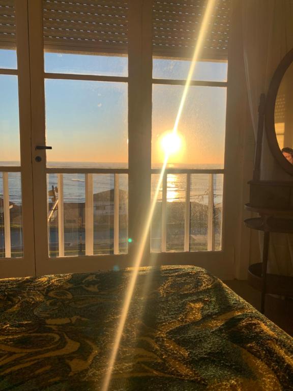 a bedroom with a bed and a window with the sunset at Mar del Plata frente al mar Biblioteca in Mar del Plata