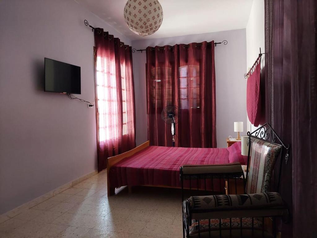 a bedroom with a pink bed and red curtains at chambre Noix de Coco résidence Chahrazad in Sfax