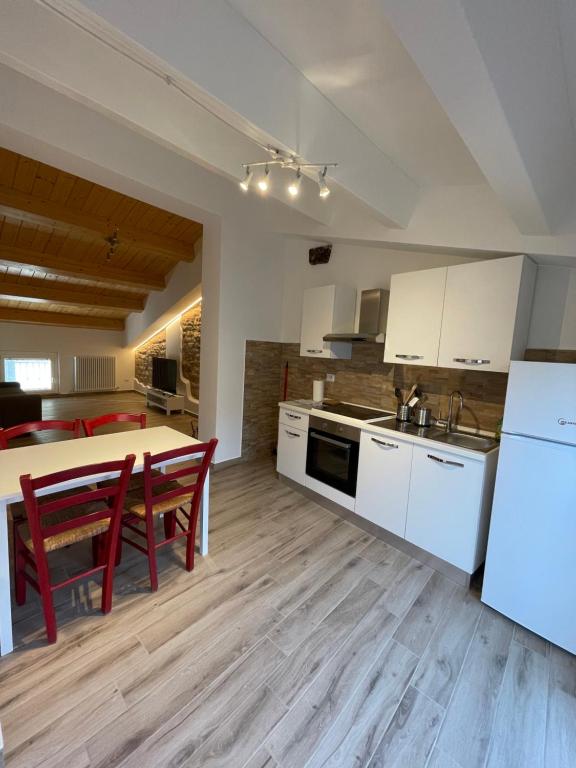 eine Küche mit weißen Schränken und einem Tisch mit roten Stühlen in der Unterkunft La Corte Residence in Fabriano