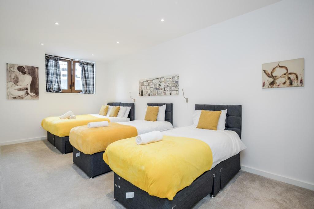 3 camas en una habitación con sábanas amarillas en Spacious 1 Bed Luxury St Albans Apartment - Free WiFi, en Saint Albans