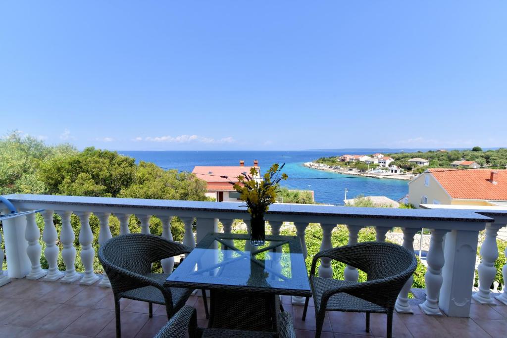 a table on a balcony with a view of the water at Apartmani Badurina - Crnika in Lun