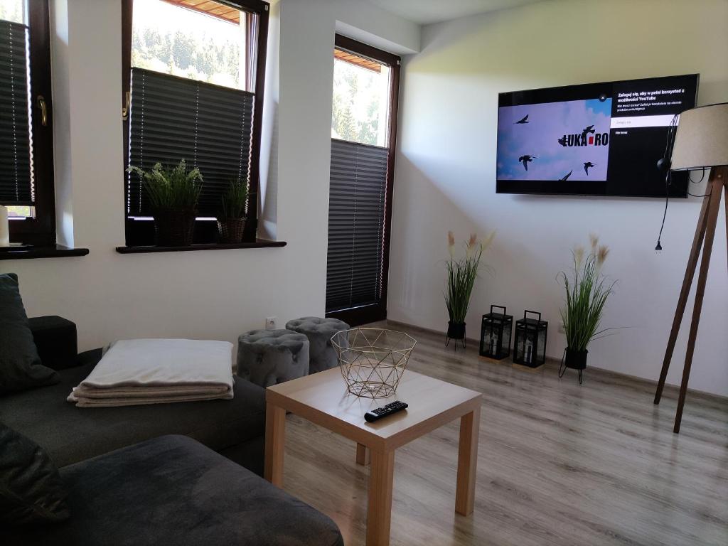 a living room with a couch and a table and a tv at Apartament Szumi Las Kletno in Kletno