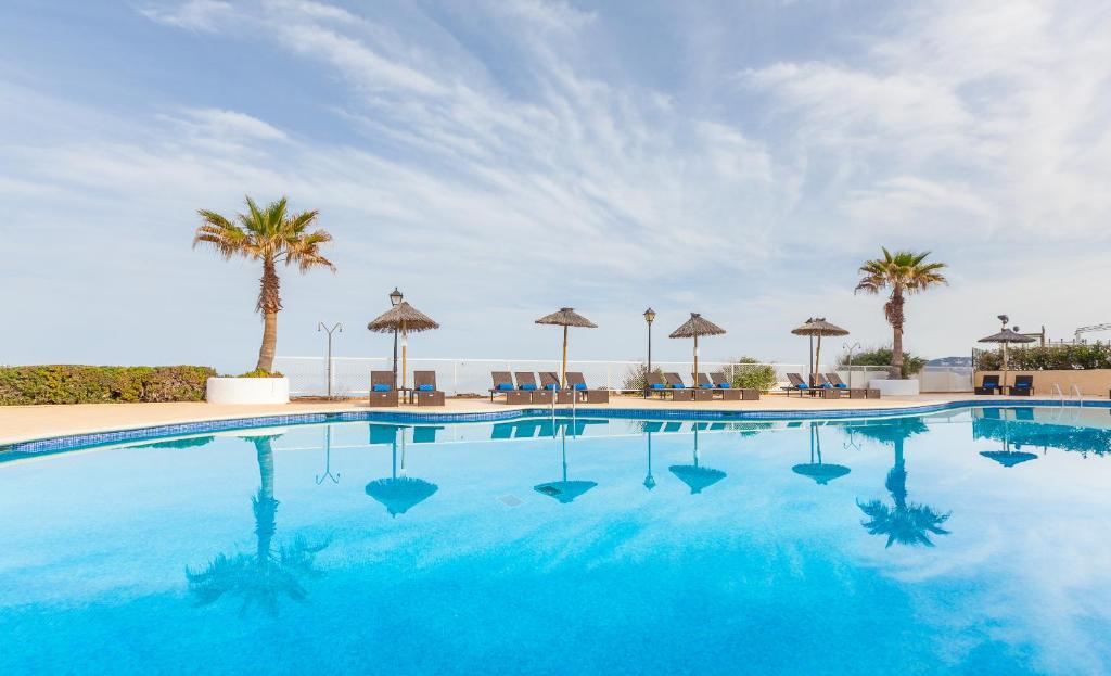 uma grande piscina com palmeiras e guarda-sóis em Marina Palace by Intercorp Hotel Group em San Antonio Bay