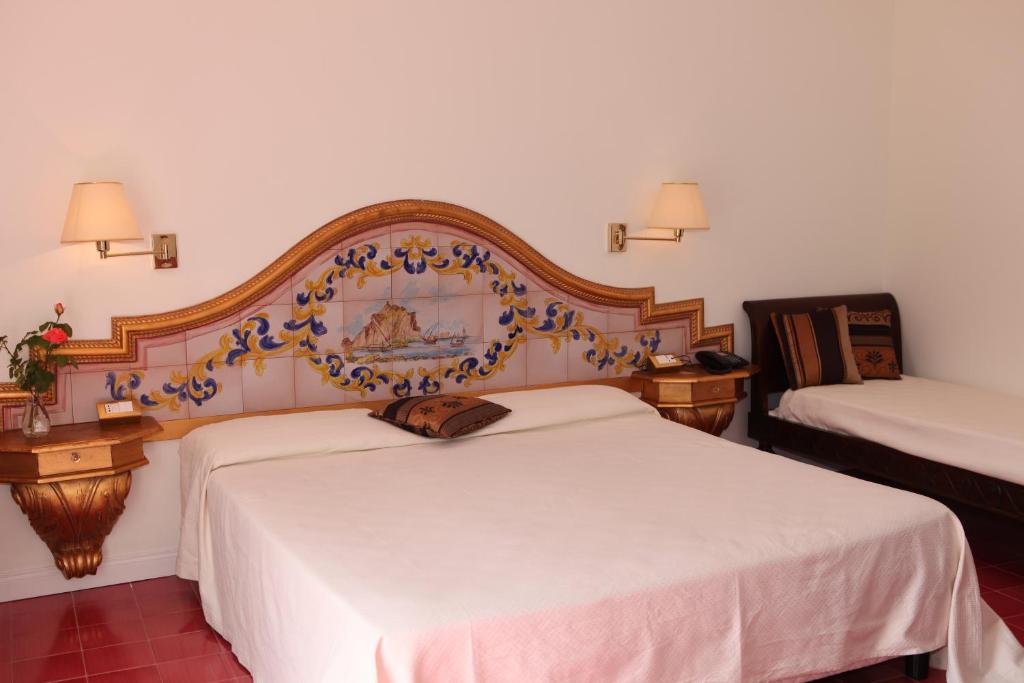 a bedroom with two beds with a large headboard at Torre Bennistra in Scopello