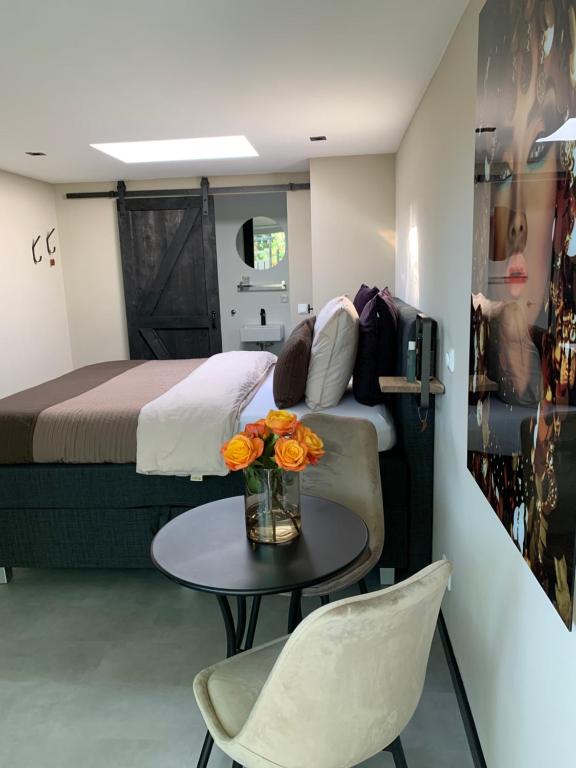 a bedroom with a bed and a table with flowers on it at Petite Maison Bennebroek in Bennebroek