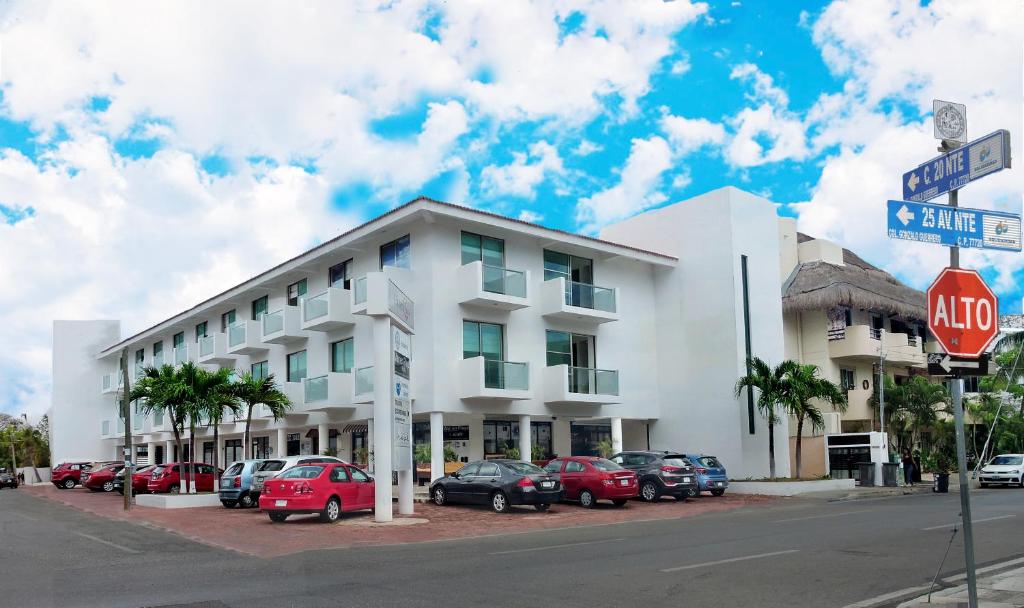 a white building with cars parked in front of it at Hotel Plaza Playa in Playa del Carmen