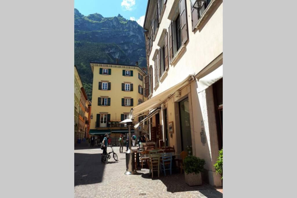 eine Stadtstraße mit Gebäuden und einem Berg im Hintergrund in der Unterkunft Schönes Altstadt-Apartment ''Dolce Vita'' inkl Parkplatz in Riva del Garda