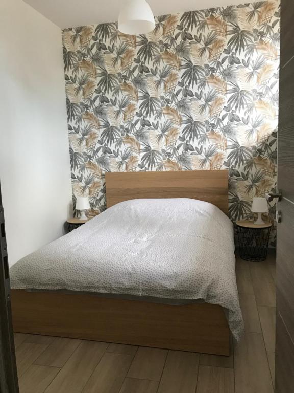 a bedroom with a bed with a floral wallpaper at Appartement au cœur du Val d&#39;Argent in Sainte-Croix-aux-Mines