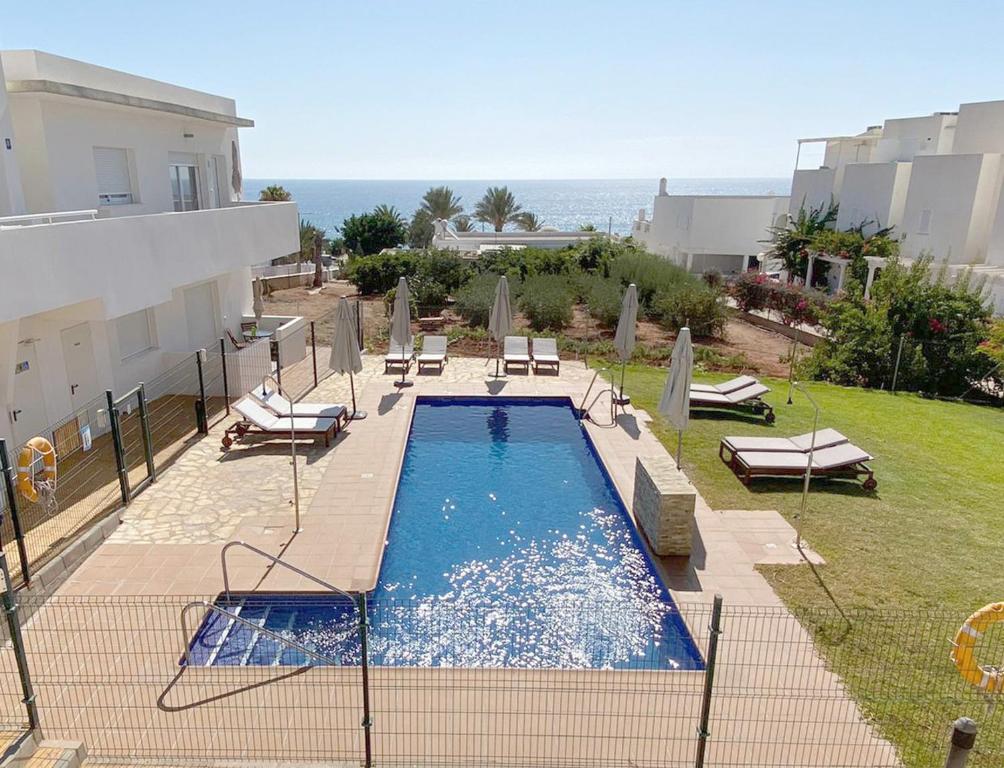 a swimming pool with chairs and the ocean in the background at Mda Playa del Cantal in Mojácar