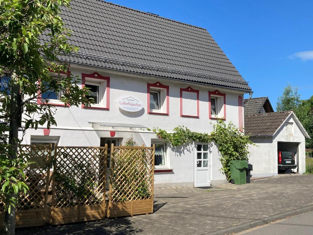 a white and red house with a fence at Ferienhaus Lieberhäuschen in Gummersbach