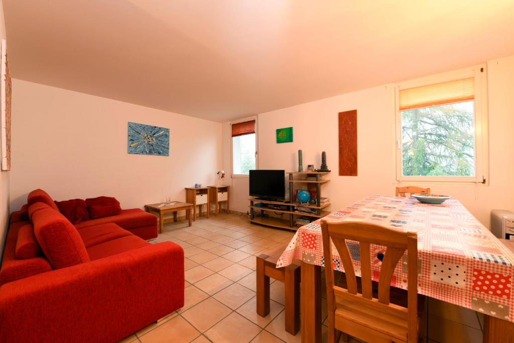 a living room with a red couch and a table at Bosco Gurin Nature & Ski in Bosco Gurin