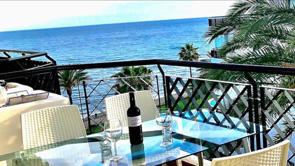 a glass table with a bottle of wine on a balcony at MI CAPRICHO 2F BEACHFRONT- Apartment with sea view - Costa del Sol in Sitio de Calahonda