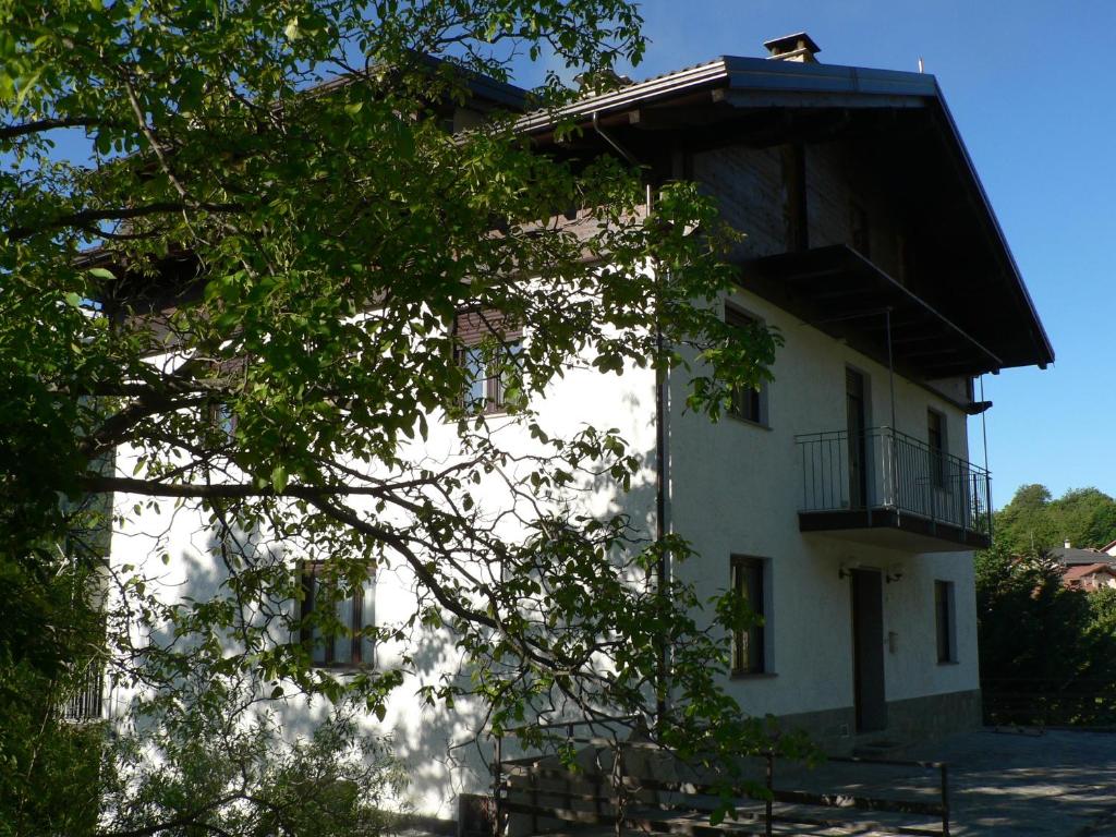 ein weißes Gebäude mit einem Balkon und einem Baum in der Unterkunft La Via del Sole in Susa