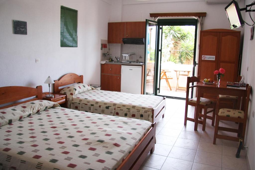 sypialnia z 2 łóżkami i biurkiem oraz kuchnia w obiekcie Evon's Rooms w mieście Fanari