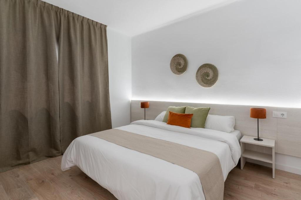 a bedroom with a large white bed and a window at Apartamentos Venecia in Lloret de Mar
