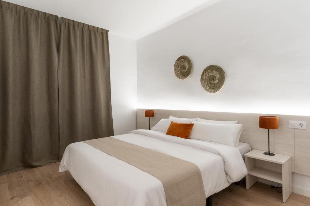 a bedroom with a large white bed and a window at Apartamentos Venecia in Lloret de Mar