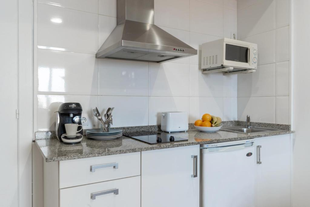 a white kitchen with a sink and a microwave at Apartamentos Venecia in Lloret de Mar