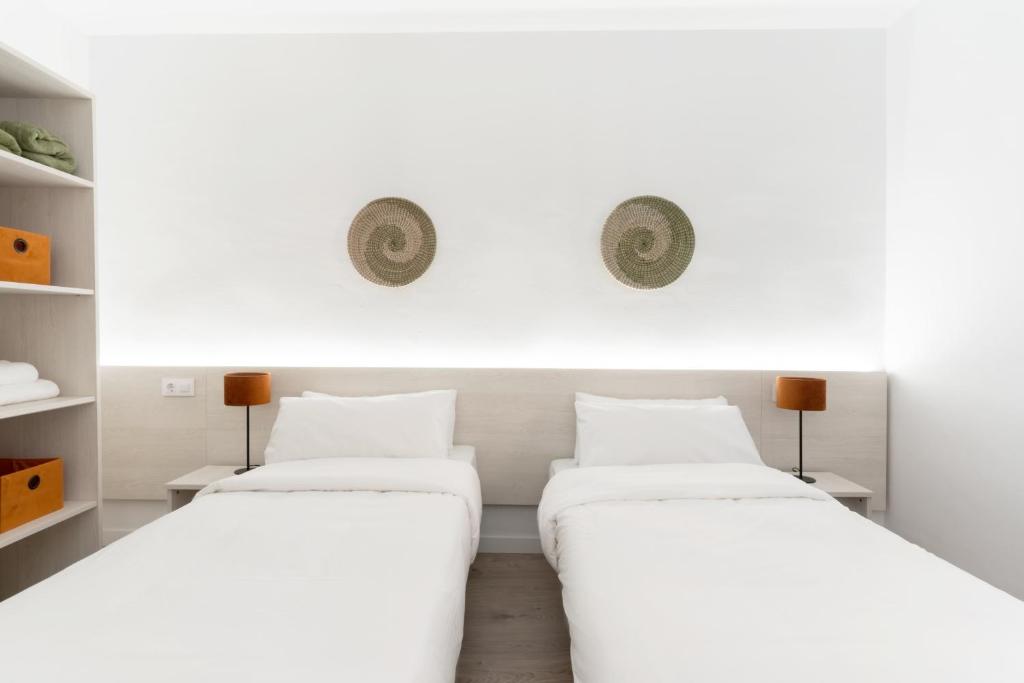 two beds in a room with white walls at Apartamentos Venecia in Lloret de Mar