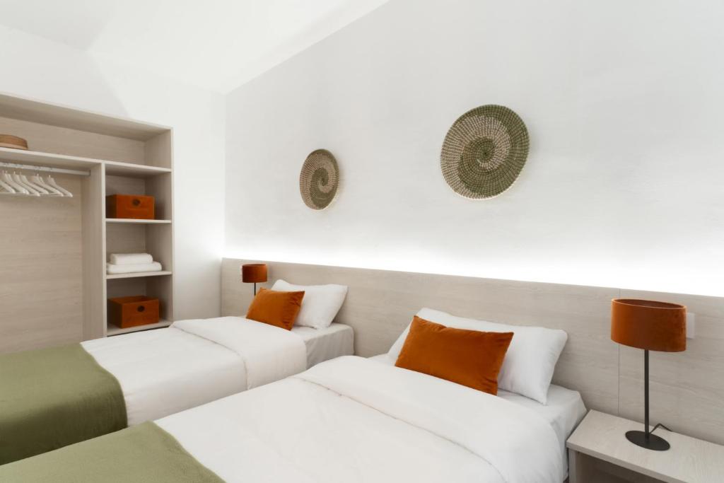 a room with two white beds and orange pillows at Apartamentos Venecia in Lloret de Mar