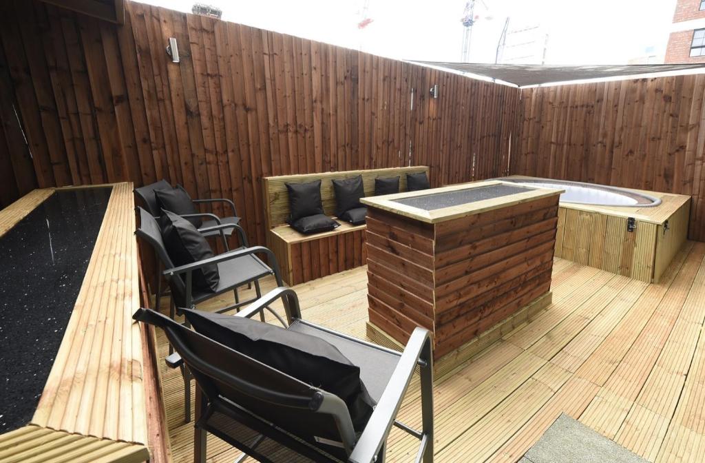 a patio with a hot tub and chairs on a deck at Slps 14 Hot Tub, Bar & Outdoor Terrace in Manchester