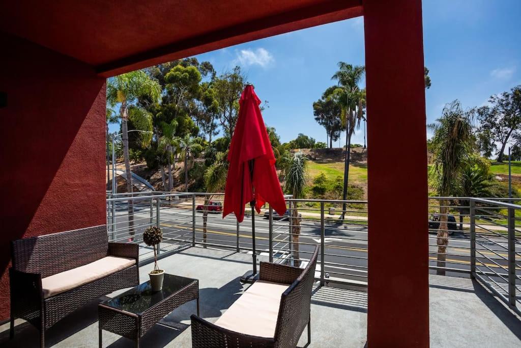 un patio con 2 sillas y una sombrilla roja en Cute Studio With Large Balcony and Great Park View, en San Diego