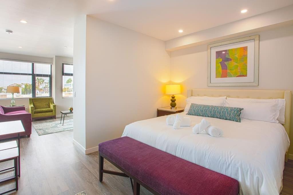 1 dormitorio con 1 cama blanca grande y banco púrpura en One Bedroom Apartment with San Diego Downtown View en San Diego