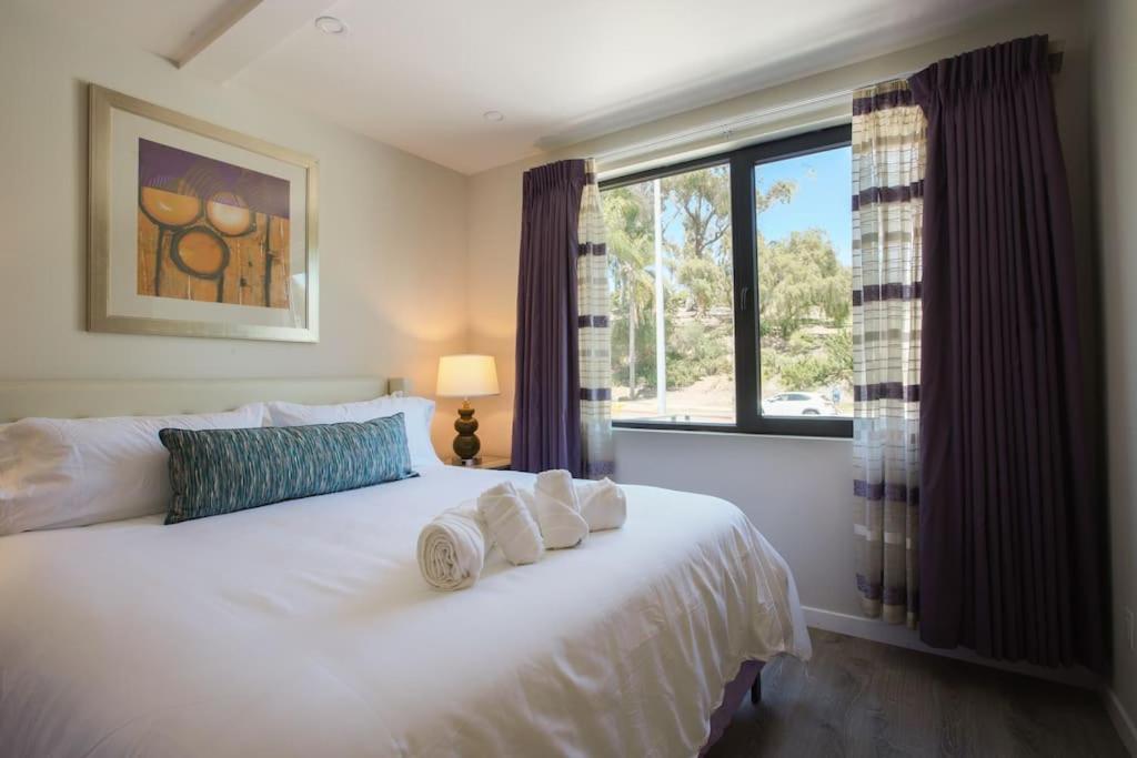 a bedroom with a white bed with towels on it at Spacious 500 sqft Studio with Balboa Park View in San Diego
