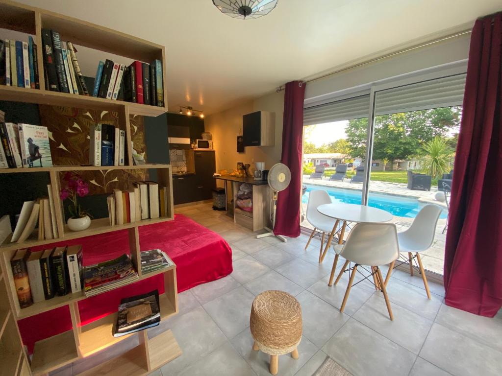 a living room with a bed and a table with chairs at Logement 2/4 pers-piscine-25mn rocade bordeaux in Baron