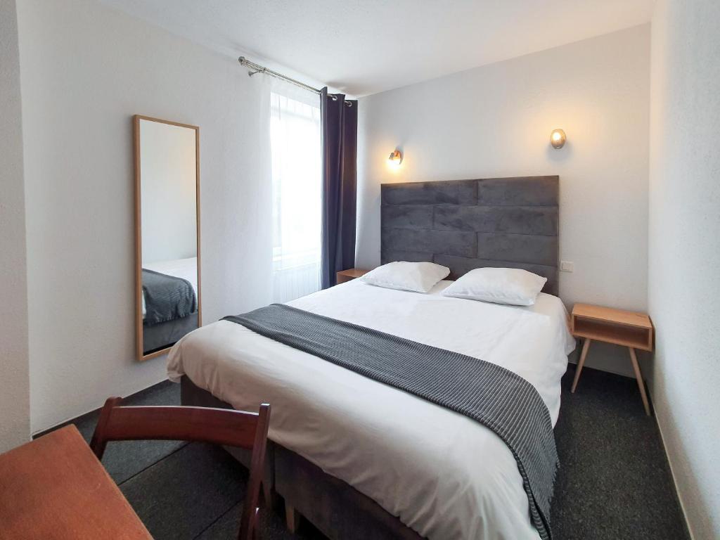 a bedroom with a large bed and a mirror at Hôtel Les Tilleuls de Pareloup à Salles-Curan in Salles-Curan