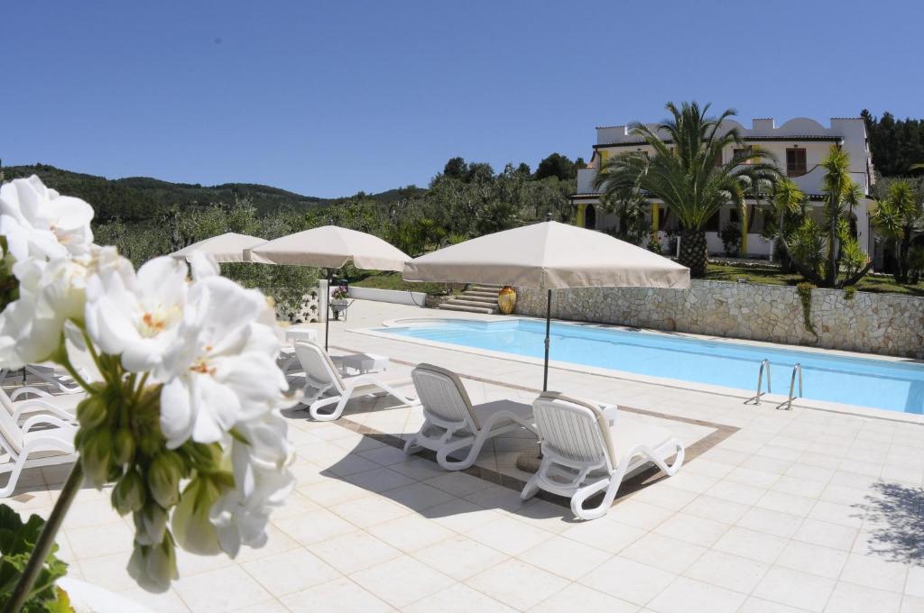 a swimming pool with white chairs and umbrellas next to a pool at Poggio di Luna Adults Only in Peschici