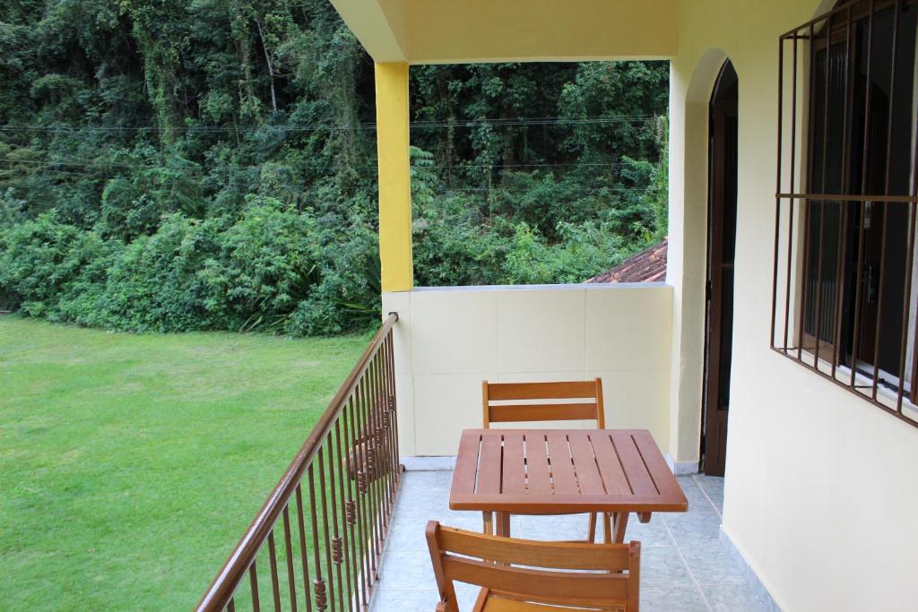 uma mesa de madeira e 2 cadeiras numa varanda em Pousada Boa Vista em Cachoeiras de Macacu
