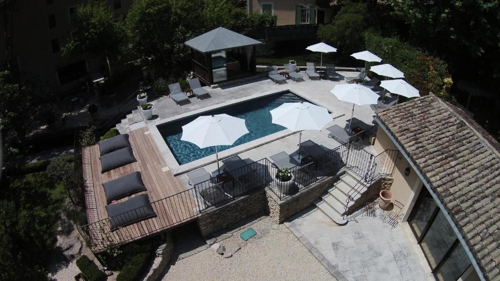 uma vista sobre uma piscina com guarda-sóis e cadeiras em Hotel du Poète em Fontaine-de-Vaucluse