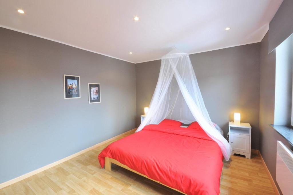 a bedroom with a red bed with a mosquito net at Les Appartements Â Vî Mâm'dî in Malmedy