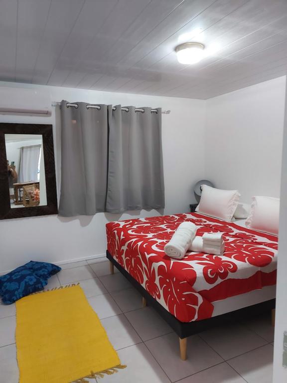 - une chambre avec un lit rouge et blanc et un miroir dans l'établissement BUNGALOW PAMATAI, à Fa'a'ā