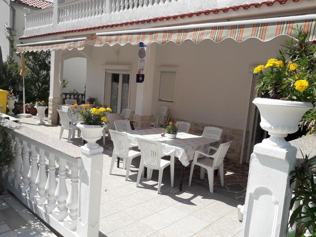 a white fence with a table and chairs on a patio at Holiday Home Marjetka in Rab