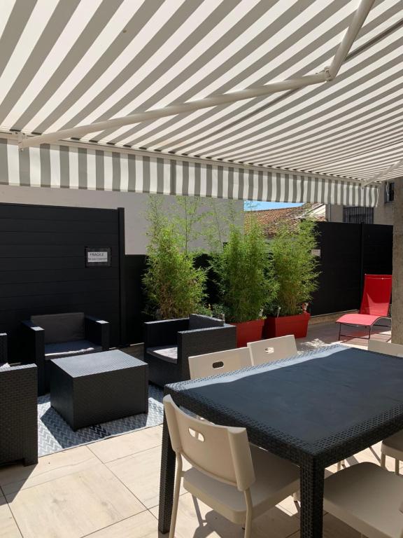a patio with a table and chairs and a white awning at Appartement la corde a linge Gruissan village avec terrasses in Gruissan