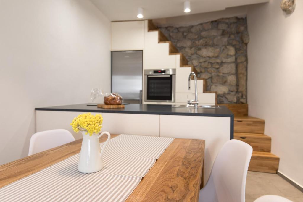 a kitchen with a wooden table with a vase of flowers at Romantic stone house in historic center of Vrbnik in Vrbnik