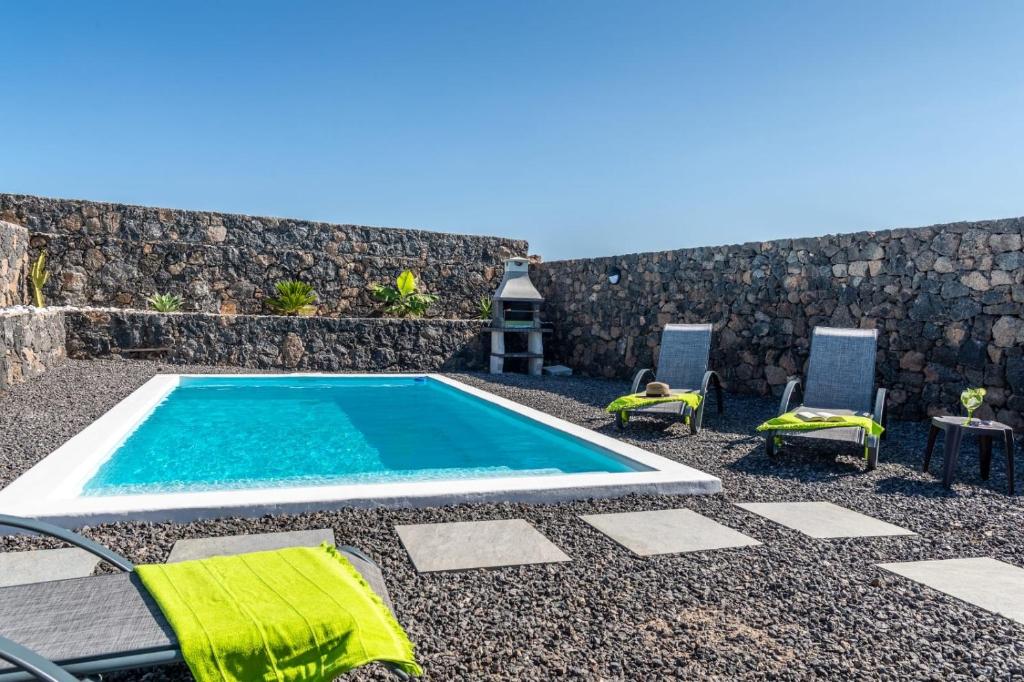 a swimming pool with two chairs and a table at Villa Alejandra in Lajares