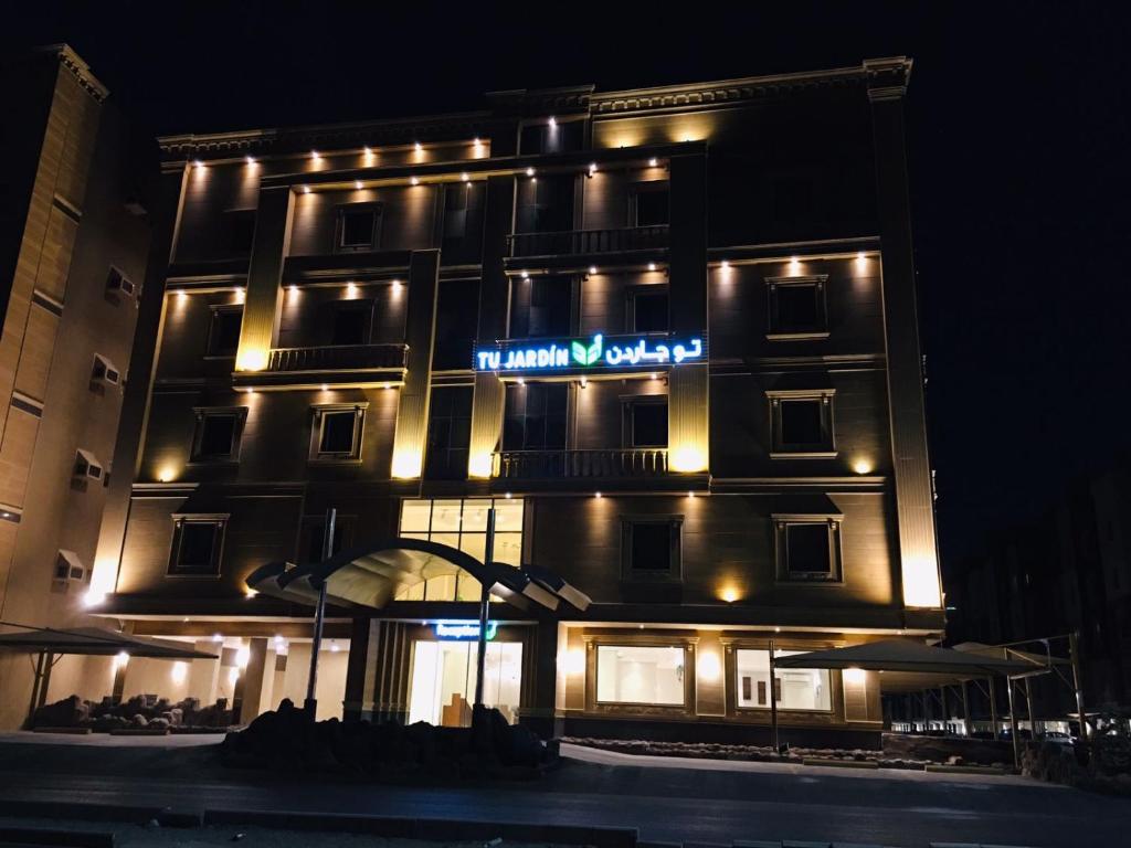 een hotelgebouw met 's nachts een bord bij Tu Jardin Al Harmain- تو جاردن الحرمين in Jeddah