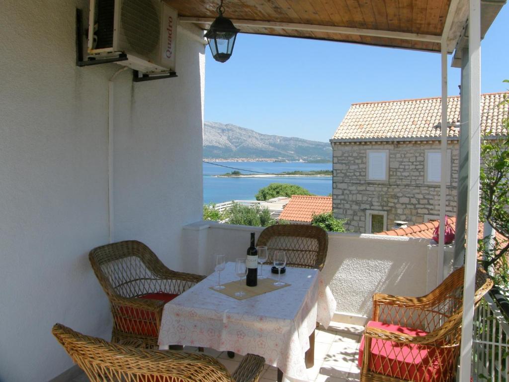 a table on a balcony with a view of the water at Apartments Ante in Lumbarda