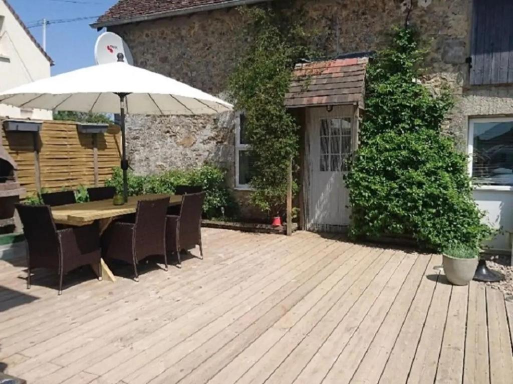 a wooden deck with an umbrella and a table and chairs at Maison Ensoleillee - in Gesnes-le-Gandelin